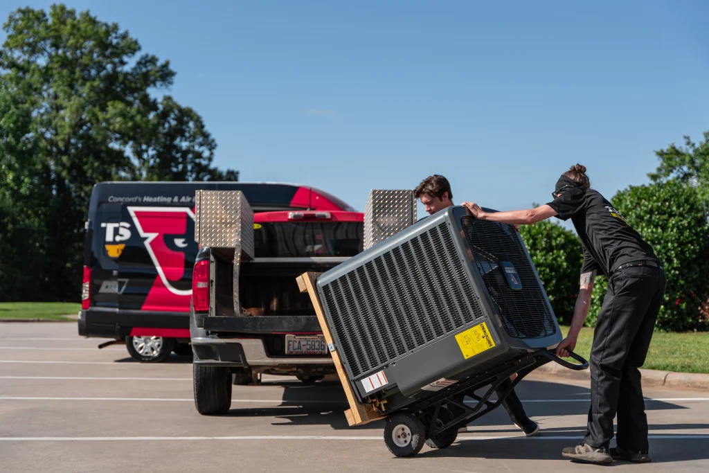 T. Byrd's HVAC techinician carrying an AC unit
