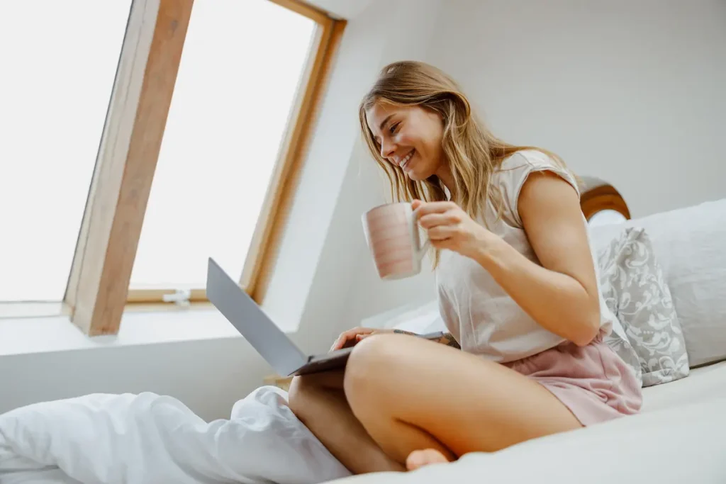 Woman sitting comfortable on a bed looking at a laptop