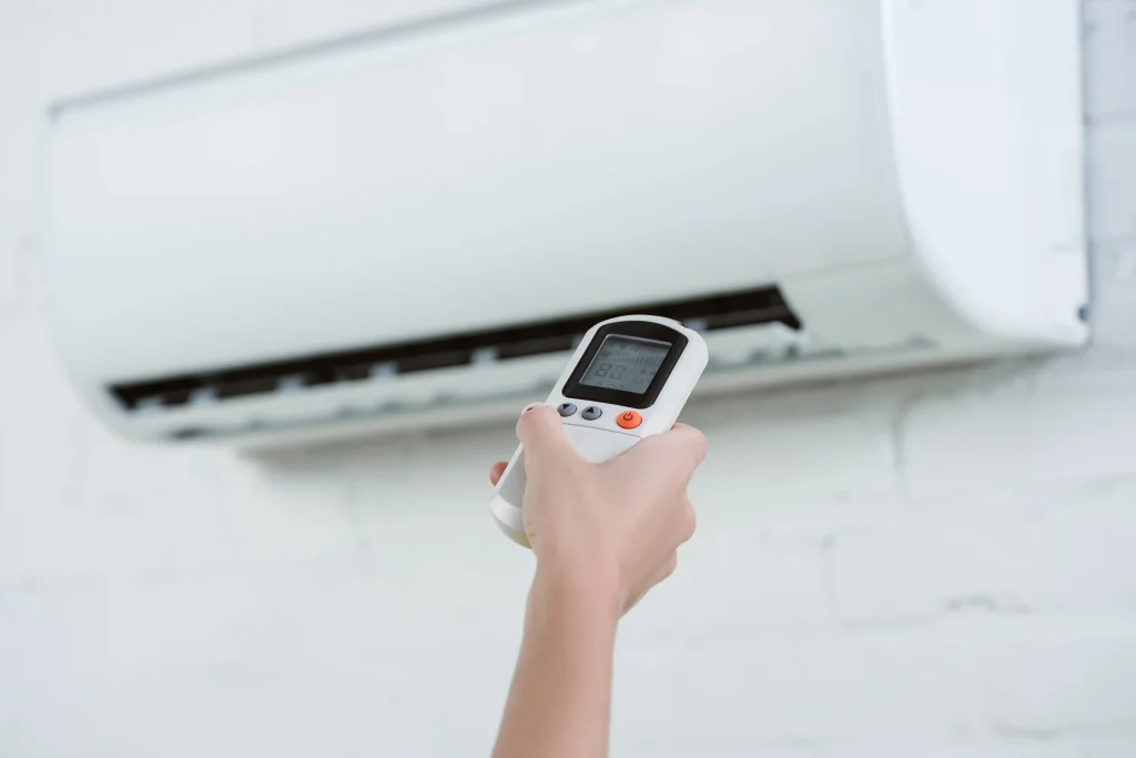 Cropped shot of woman adjusting air conditioner temperature